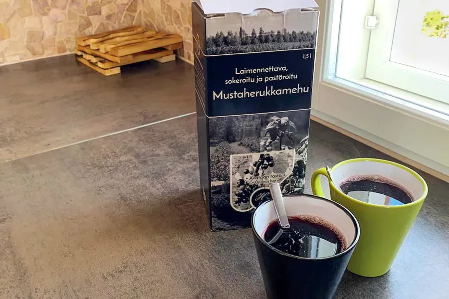 Mustaherukkamehupurkki ja kaksi kupillista mustaherukkamehua keittiön tasolla